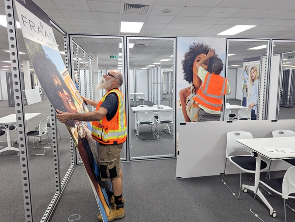 An image of a fibreboard print being installed in an Aluvision frame by a professional graphics fitter on-site